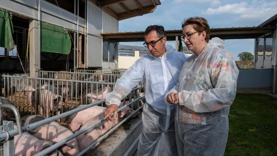 Bundesminister Cem Özdemir und seine Amtskollegin, Bundesministerin Klara Geywitz, stehen vor einem Schweineauslauf