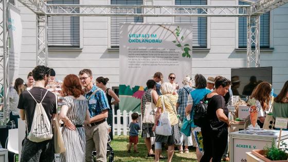 Gruppenbild: Besucherinnen und Besucher beim Tag der offenen Tür im BMEL, im Hintergrund ein Plakat mit der Aufschrift "Vielfalt im Ökolandbau"
